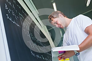 Handsome college student solving a math problem during math class