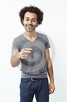 Handsome confident african man smiling pointing finger at camera. White background.