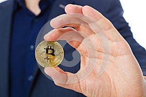 Handsome confident businessman holding gold bitcoin coin. Selective focus. Business success concept.