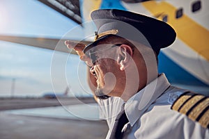 Handsome confident male wearing white shirt and tie standing near the big civil airplane