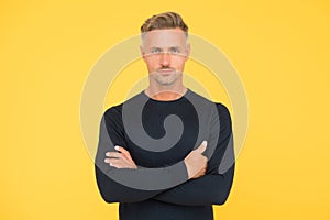 Handsome confident man crossed hands has stylish hairdo and groomed face bristle on yellow background, mens beauty