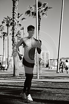 Handsome confident sporty guy running in the morning along beach. Black and white photo