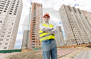 Handsome construction engineer standing on building site