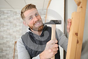 handsome construction man using hammer to nail wood