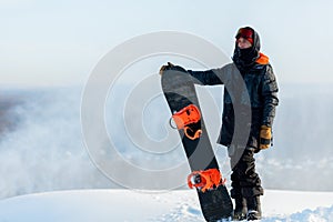 Handsome cool man with snowboard on mountain top.