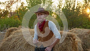 Handsome cowboy posing near hay on his farm