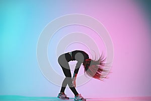 Handsome creative female dancer posing in studio against colorful background