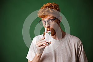 Handsome curly readhead bearded man in glasses, drinking water,