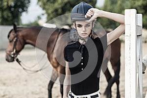 Handsome cute rider standing near brown hourse. Blurred background