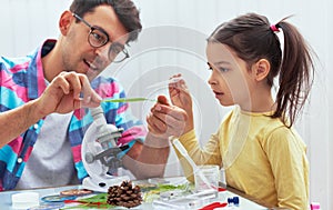 Handsome dad and cute daughter study biology and chemistry lesson with microscope. Little girl with father doing science photo