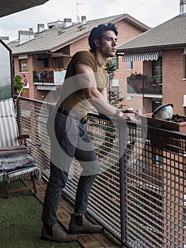 Handsome dark haired young man standing in a balcony