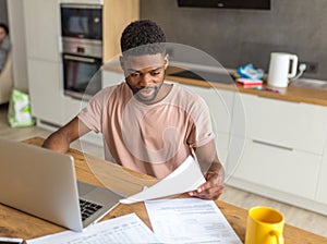 African man using laptop while caucasian girlfriend standing lonely at kitchen