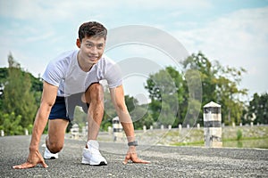 Handsome determined athletic Asian man preparing to run, steady starting position