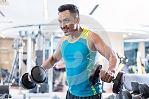 Handsome determined young man exercising with dumbbells in a mod