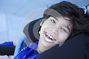 Handsome disabled boy in wheelchair smiling, looking up