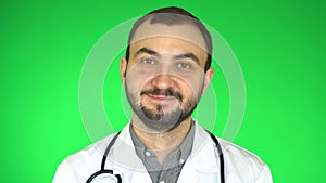 Handsome doctor man looking at camera and smiling green screen background