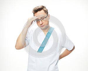 Handsome doctor man wearing medical uniform tired rubbing forehead, feeling fatigue and headache.