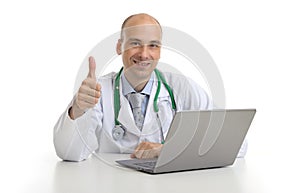 Handsome doktor sitting at a desk with laptop photo