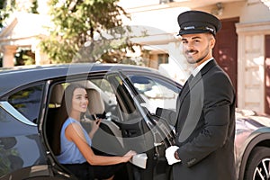 Handsome driver opening car door for young businesswoman