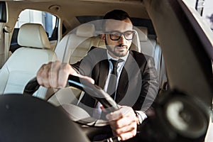 handsome driver in suit driving car and looking