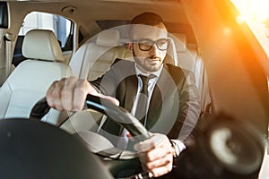 handsome driver in suit and glasses driving auto