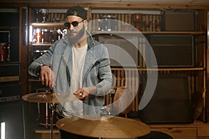 Handsome drummer standing nearby drum set with metallic gold plate