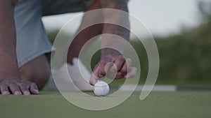 Handsome eastern man man blowing golf ball in the hole and shows thumbs up. Summer leisure