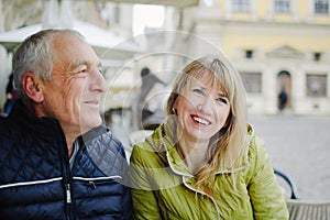 Handsome elderly man is embracing his young blonde wife spending time together outdoors in the ancient city during early