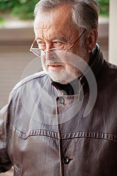 Handsome elderly man in glasses and leather jacket close-up