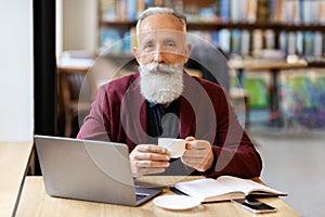 Handsome elderly man planning his day while having coffee