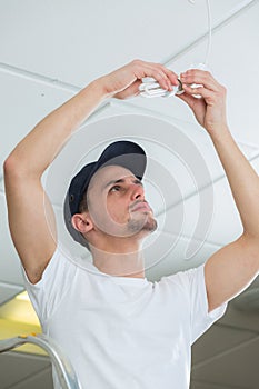 Handsome electrician changing lightbulb