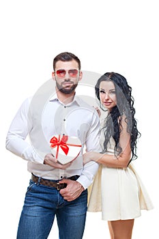 Handsome elegant guy is presenting a heart shaped gift to his beautiful girlfriend and smiling, valentines day theme
