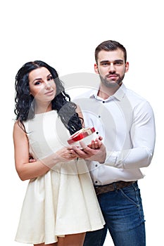 Handsome elegant guy is presenting a heart shaped gift to his beautiful girlfriend and smiling, valentines day theme