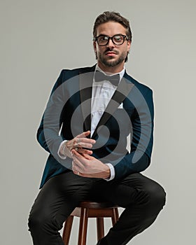 handsome elegant man with glasses looking forward and adjusting rings