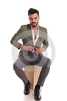 Handsome elegant man unbuttoning suit jacket while sitting