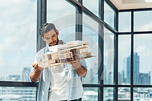 Handsome engineer hold architectural model while inspect house model. Tracery.