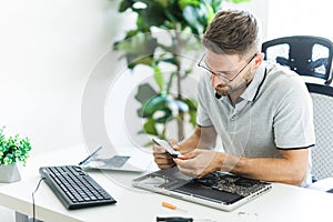 Handsome engineer repairing laptop computer.