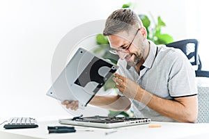 Handsome engineer repairing laptop computer.