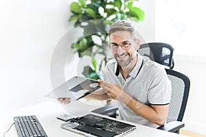 Handsome engineer repairing laptop computer.