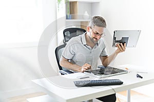 Handsome engineer repairing laptop computer.