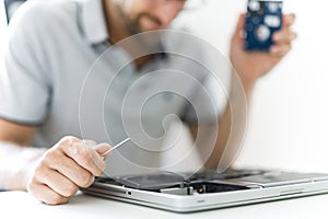 Handsome engineer repairing laptop computer.