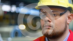 Handsome engineer walking in a factory. Industrial background