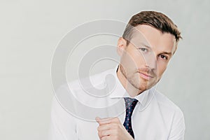 Handsome entrepreneur in white shirt looks at camera, listens attentively to interlocutor, talks business. Isolated on white