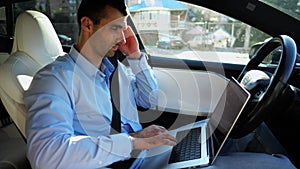 Handsome entrepreneur working on notebook while riding an autonomous self driving electric car at urban road. Male