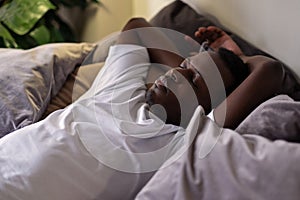 Handsome ethnic black african man resting in bed sleeping or napping.