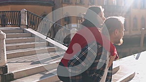 Handsome european man carrying on his back gorgeous asian woman in the streets of Venice. Young hipster couple in love