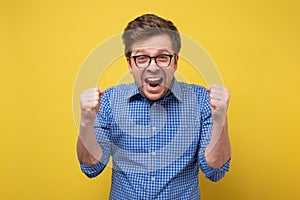 Handsome excited man happy smile looking at camera, hold arm hands fist raised up gesture.