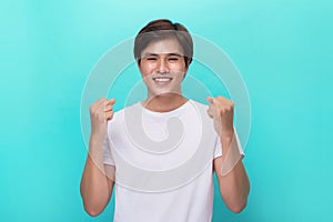 Handsome excited man happy smile looking at camera, hold arm hands fist raised up gesture, young guy wear t-shirt, isolated over