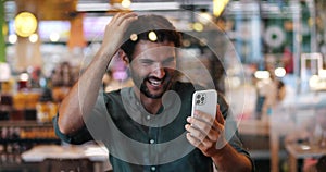 Handsome excited young dark-haired bearded man, a football fan, watching a soccer match on his phone, expressing