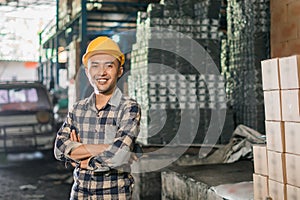 handsome factory worker smiling while standing with crossed hands